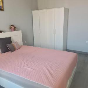 1 dormitorio con cama rosa y armarios blancos en Centru Oradea, en Oradea
