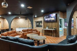 a living room with leather furniture and a tv at Phuniphat Pool Villa in Nong Prue