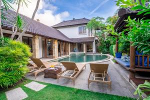 a backyard with a pool and chairs and a house at Villa Aveli Seminyak by Best Deals Asia Hospitality in Seminyak