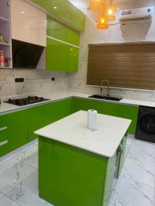 uma cozinha com armários verdes e um balcão branco em Three bedroom duplex at chevron lekki, Lagos em Lekki