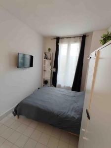 a bedroom with a bed and a television in it at Cozy Polo's House in Bagnolet