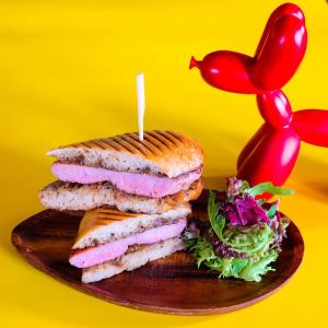 a sandwich on a wooden plate with a red chili pepper at Eastin Grand Hotel Sathorn in Bangkok