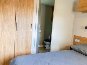 a bedroom with a bed and a bathroom with a toilet at Mobil-home CAMARGUE in Vias