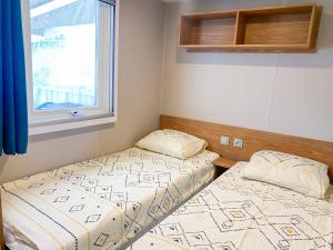 two twin beds in a room with a window at Mobil-home CAMARGUE in Vias
