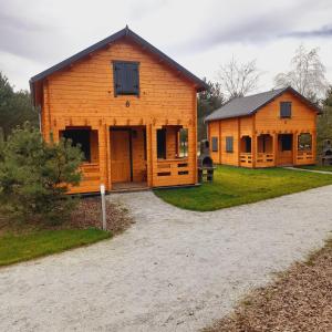 een groot houten gebouw naast een huis bij Osada Gardenia in Ślesin