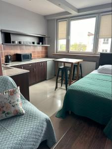 a bedroom with a bed and a table and a kitchen at Apartamenty Komfort in Częstochowa