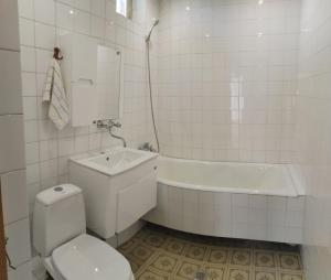 a white bathroom with a toilet and a bath tub at GUEST HOUSE SG in Norakert