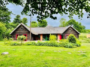una casa con persianas rojas en un patio verde en Resilienz und Entspannung pur! Neue LODGE am See - ideal für Gruppen und Familien, en Mustin