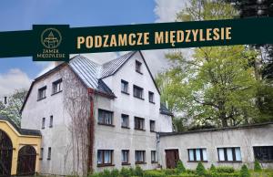 a sign that reads poolemite micocyrise next to a white building at Zamek Międzylesie in Międzylesie