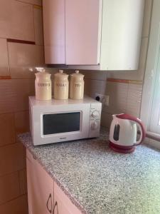 a microwave on a kitchen counter with three mugs on it at Cute Little Casita in Mijas