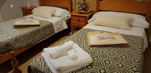 two beds in a hotel room with towels on them at Vila Vilariño Albergue Hotel & Restaurante in Ourense