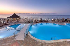 a pool at a resort with the ocean in the background at Alexander Beach Hotel & Village Resort in Malia