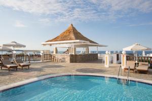 uma piscina de resort com um gazebo e o oceano em Alexander Beach Hotel & Village Resort em Mália