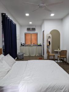 a bedroom with a large white bed and a table at Rods Homestay - Kg Agong Penaga in Kepala Batas