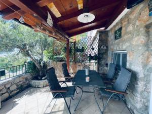 eine Terrasse mit einem Tisch, Stühlen und einer Steinmauer in der Unterkunft Kuća za odmor “Dida” in Stinica
