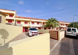 ein Gebäude mit zwei Autos auf einem Parkplatz in der Unterkunft Angela Beach Place in Vila Baleira