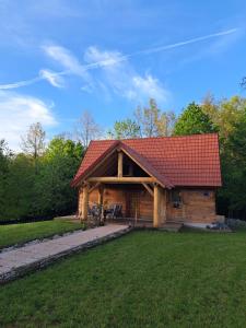 Cabaña de madera con techo rojo en la hierba en Guest house Mihovil, en Slunj