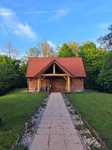 Cabaña de madera con techo rojo y paseo en Guest house Mihovil, en Slunj
