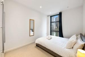 a white bedroom with a bed and a window at Londwell, Canary Wharf River Thames Balcony Suite in London