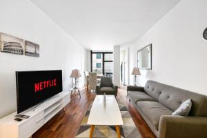 a living room with a couch and a tv at Londwell, Canary Wharf River Thames Balcony Suite in London