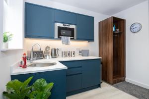 una cocina con armarios azules y fregadero en Morecambe Bay Studio Apartments with Free Parking By Beach Front en Morecambe