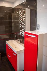 La salle de bains est pourvue d'une armoire rouge à côté d'un lavabo. dans l'établissement Garden Apartments, à Szeged