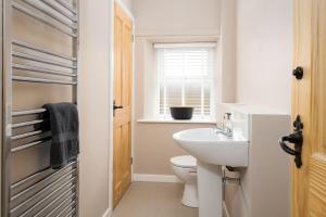 een badkamer met een wastafel en een toilet en een raam bij Lyme Grass in Bamburgh +19 foto's