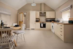een keuken met witte kasten en een tafel en stoelen bij Lyme Grass in Bamburgh