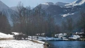 a snow covered river with trees and mountains in the background at Reflets montagnards in Vignec +3 photos