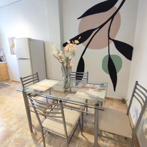 uma mesa de jantar em vidro com cadeiras e um vaso com flores em Madi01 em Atenas