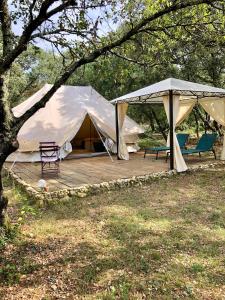 Zelt mit Stühlen und Stühlen auf einer Holzterrasse in der Unterkunft Spa Les Jardins De Chiron Lodges et Tiny House dans le sud in Sauve