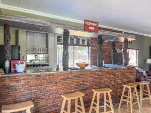 a bar with a brick wall and stools at My Africa Adventure Farm in Hoedspruit