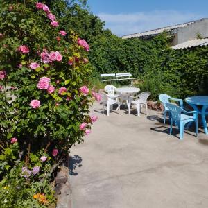 een patio met tafels en stoelen en roze rozen bij Guest house on Akmatbai-Ata 29 in Cholpon-Ata