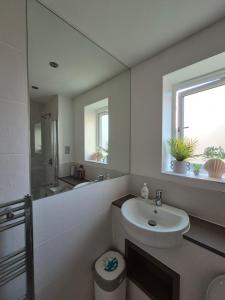 La salle de bains blanche est pourvue d'un lavabo et d'un miroir. dans l'établissement Room in a pristine 4 bed home in Broomfield, à Chelmsford