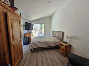 een slaapkamer met een bed en een tv aan de muur bij La maison champêtre - Rendez-vous en Provence in Althen-des-Paluds