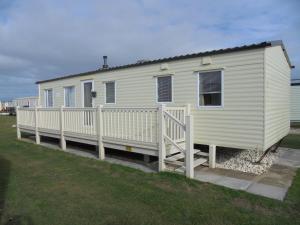a white mobile home with a white fence at 8 Berth Coral Beach (Mirage Super) in Ingoldmells