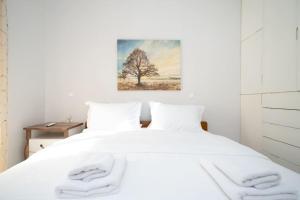 a bedroom with a white bed with a tree painting on the wall at Romance Dream Meteora 2 in Kalabaka