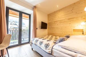 um quarto com uma cama e uma grande janela em Apartamenty GoMiś Zakopane em Zakopane