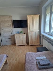 - une chambre avec un lit, des placards en bois et une télévision dans l'établissement Pokoje Bory Tucholskie, à Tuchola