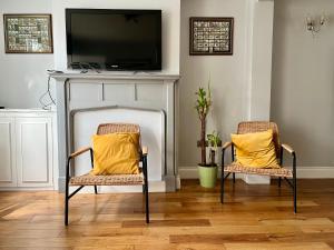 2 sillas con almohadas amarillas en una habitación con TV en The Windmill en Busheyheath