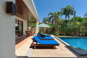 a patio with blue lounge chairs and a swimming pool at Baan Bua Estate by Tropiclook in Nai Harn Beach
