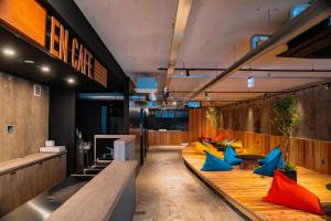 a lobby with wooden floors and blue and orange chairs at EN PLUS sauna and capsule bed 男性専用 in Kochi