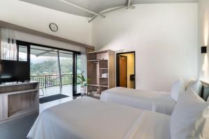 a bedroom with two beds and a television and a balcony at Pelangi Park Hotel & Resort in Pasirkuda