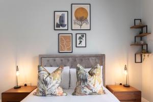 a bedroom with a bed with pillows and pictures on the wall at Elliot Oliver - Stylish 2 Bedroom Apartment With Parking In The Docks in Gloucester
