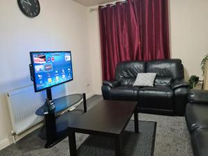 a living room with a leather couch and a flat screen tv at Ideal Apartment close to the Hustle and Bustle in Ashton under Lyne