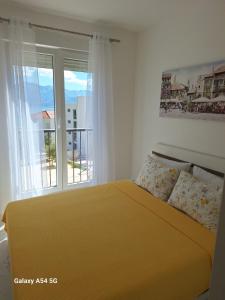 a bedroom with a yellow bed and a window at Sun&sea in Ðenovići