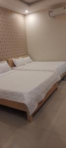 een slaapkamer met 2 bedden en witte lakens bij Nhà Nghỉ Kim Cương in Rach Gia