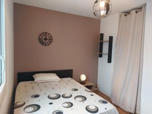een slaapkamer met een bed en een klok aan de muur bij l' Iris in Orvault