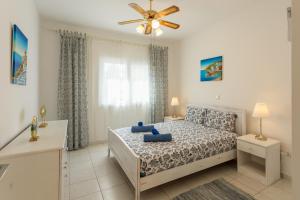 Schlafzimmer mit einem Bett und einem Deckenventilator in der Unterkunft Regina Gardens Lovely Apartment in Paphos City