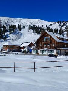 eine Ski-Lodge mit einem schneebedeckten Berg im Hintergrund in der Unterkunft Apartments Alpenpark Turrach by ALPS RESORTS in Brandstätter